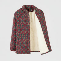 A women's quilted jacket with a red, green, and beige geometric pattern, featuring a soft cream fleece lining, shown on a hanger against a white background.