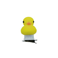 A small yellow duck-shaped hair clip with black eyes, a peach beak, a white collar, and a black metal clip base, shown against a plain white background.