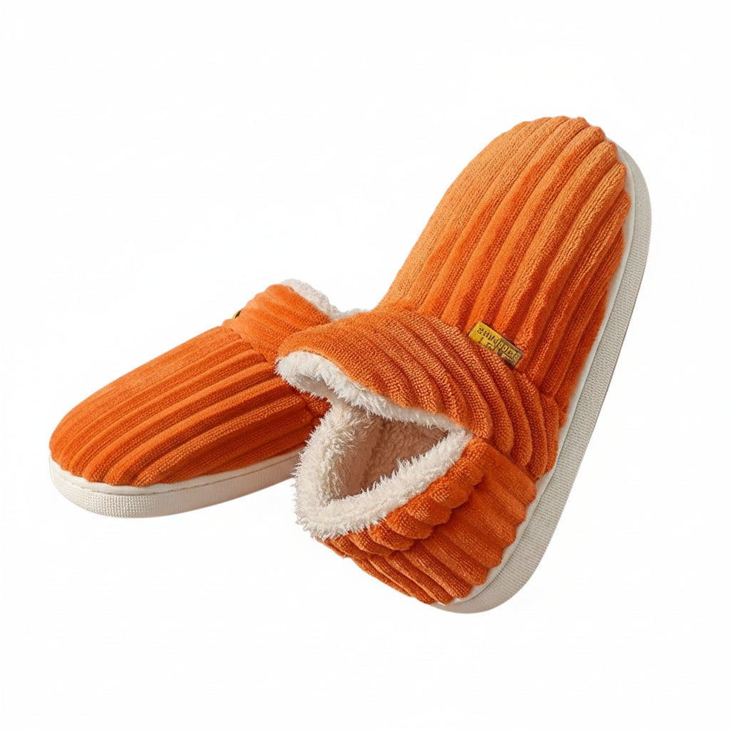 Orange slippers with white soles held by a person against a brown background