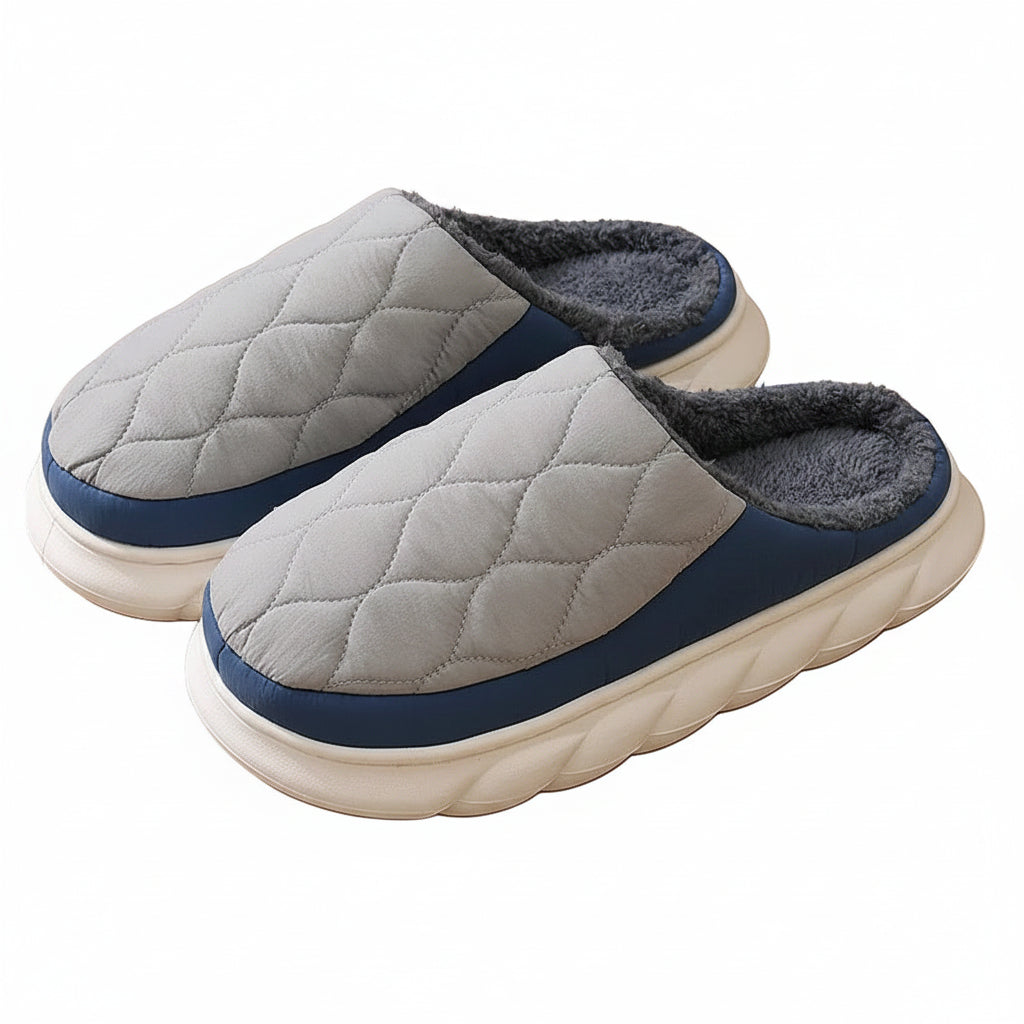 Pair of gray and blue quilted slippers on a wooden floor.
