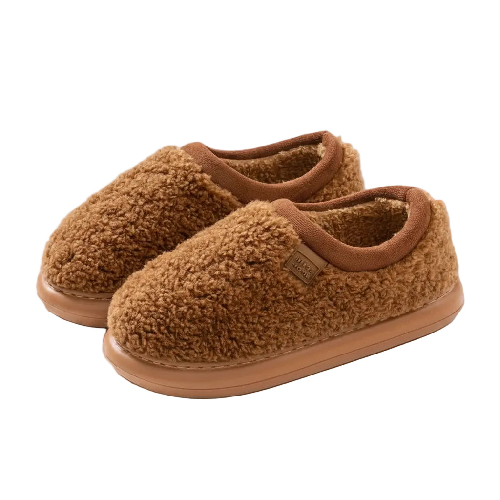 A pair of cozy brown sherpa fleece slip-on slippers with a soft tan sole, shown on a solid beige background.