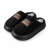 Black slippers with brown labels on a wooden floor