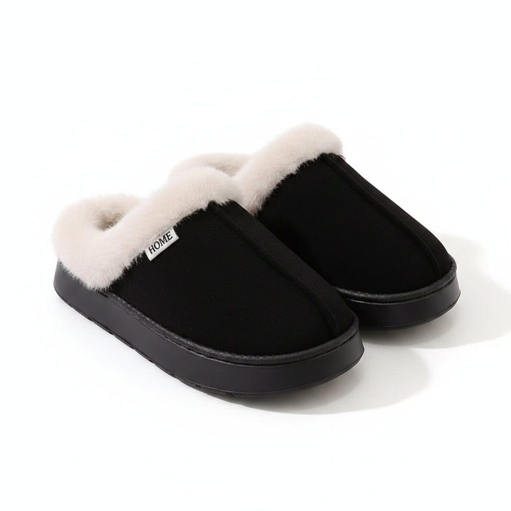 A pair of black slip-on slippers with thick, fluffy cream faux-fur trim around the openings, photographed on a light beige surface with a white ribbed blanket in the background.
