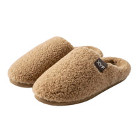 Pair of tan slippers with a brand label on a beige background