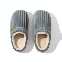 Pair of gray slippers with a textured surface on a brown background