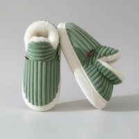 Green slippers with white fur lining on a light background