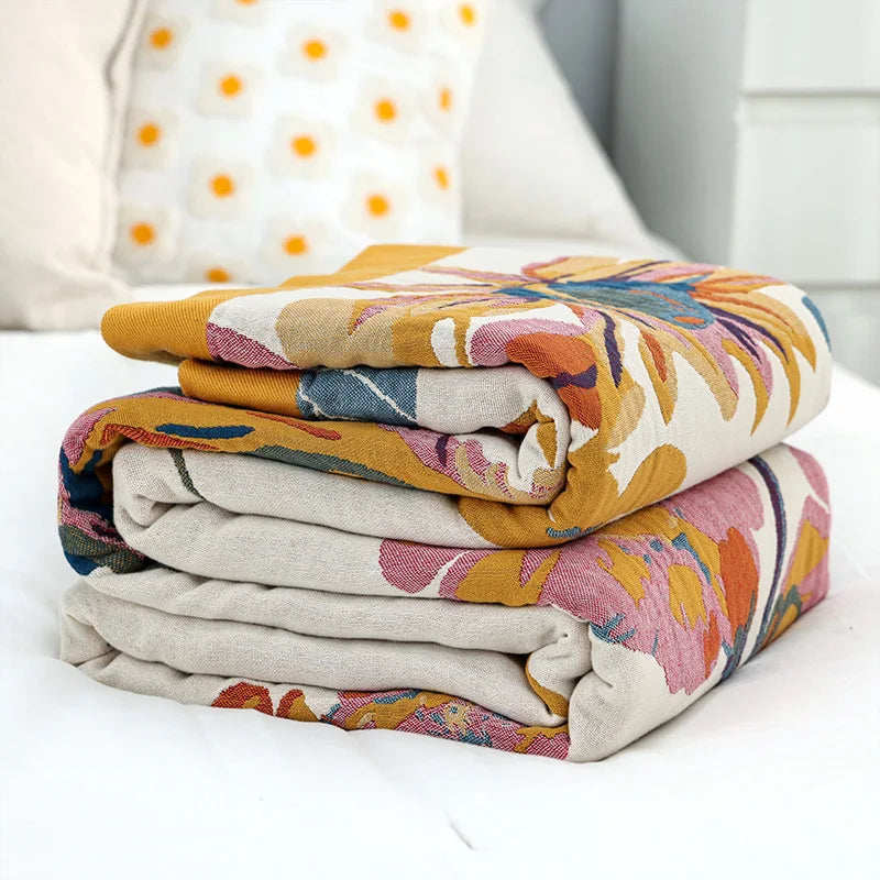 Stack of colorful patterned blankets on a white surface