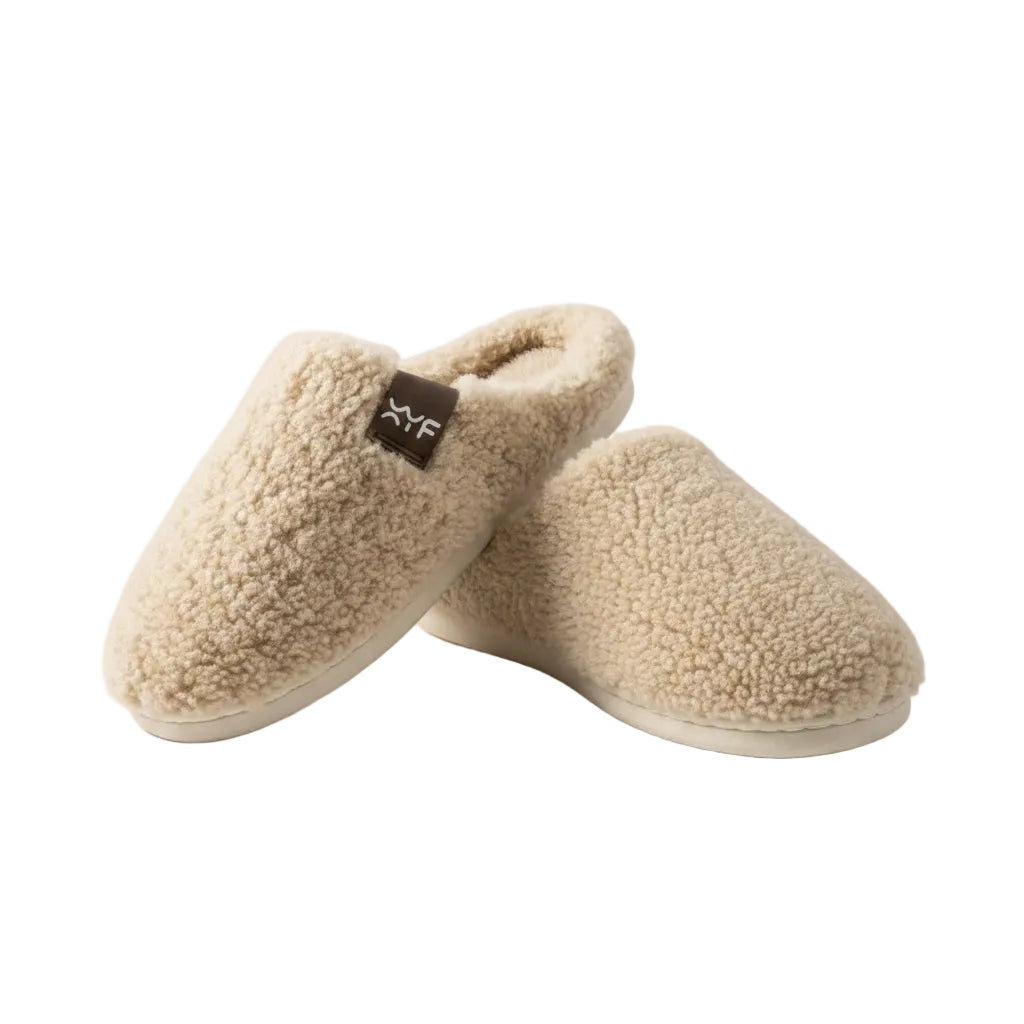 Pair of beige slippers with a brand tag on a beige background
