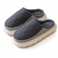 Pair of gray quilted slippers on a wooden floor