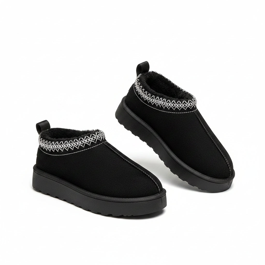 Black slip-on shoes with white pattern on a fluffy white surface