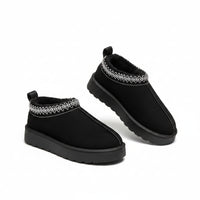 Black slip-on shoes with white pattern on a fluffy white surface