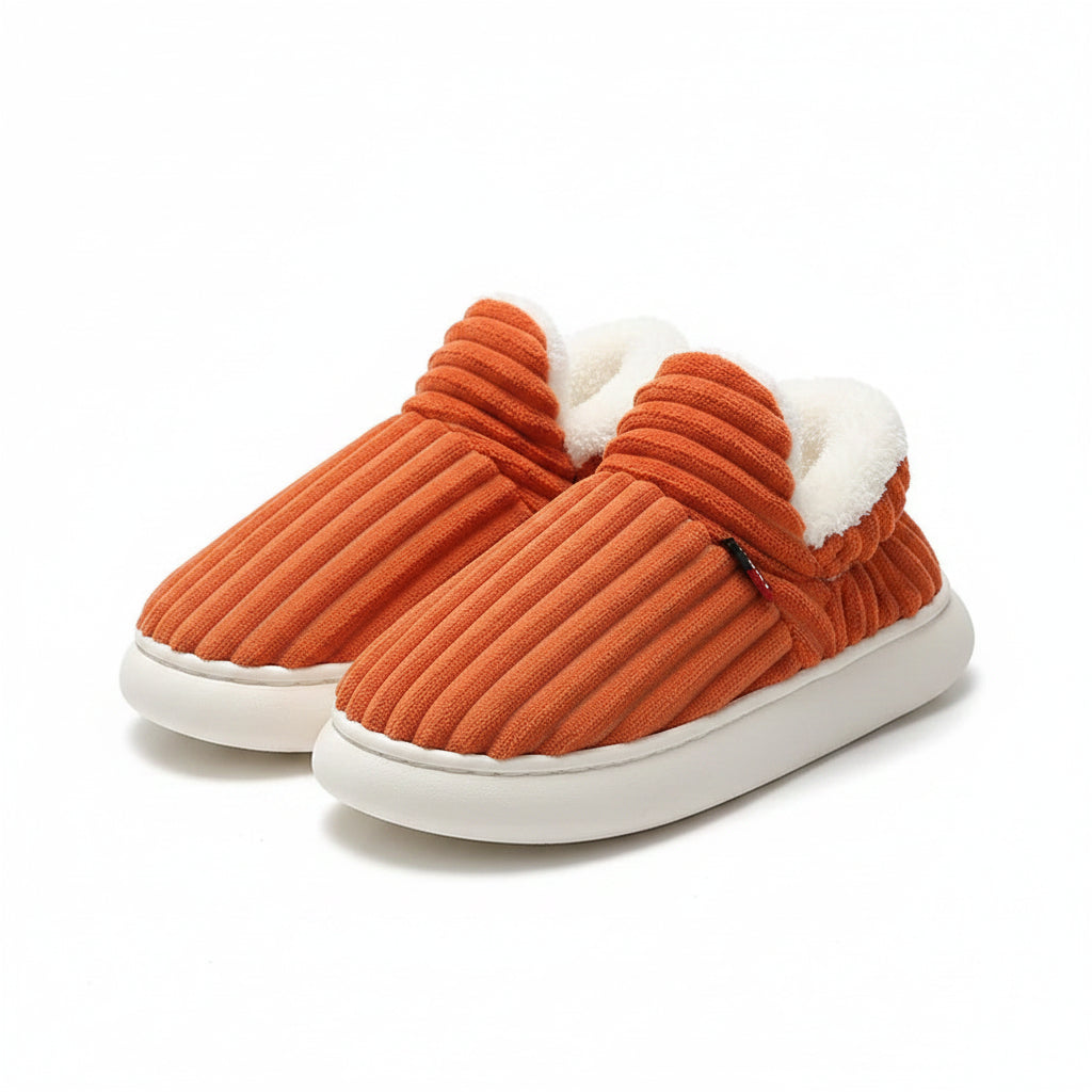 Pair of orange slippers with white soles on a light background