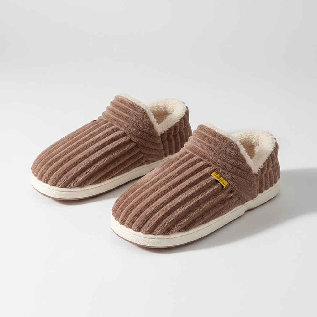 Brown slippers with white soles worn by a person on a brown background