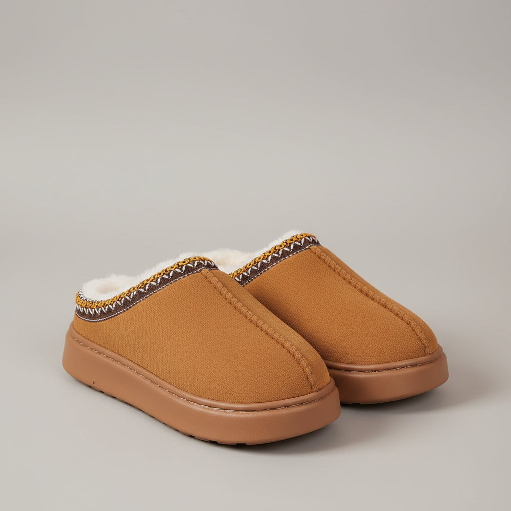 Brown slippers with decorative trim worn indoors on a textured floor.