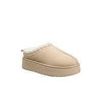 A pair of beige slip-on slippers with a soft white faux-fur lining and a decorative braided trim around the collar, shown on a plain white background.