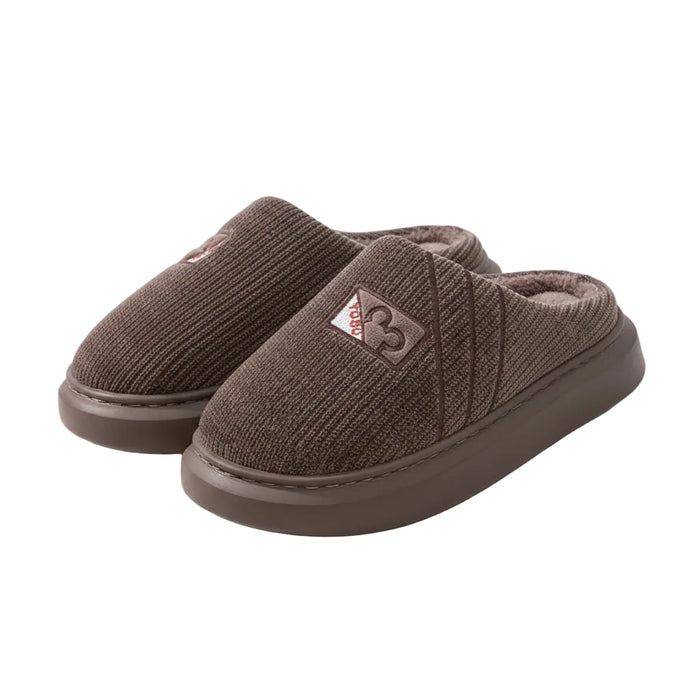 Brown slippers with a brand logo on a wooden floor