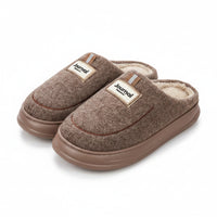 Pair of brown slippers with 'Journal' label on a wooden floor.