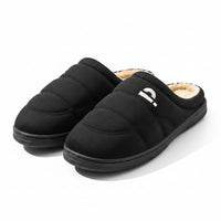 Black slippers with beige lining on a wooden surface