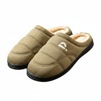 Pair of green slippers with quilted design on a wooden floor.