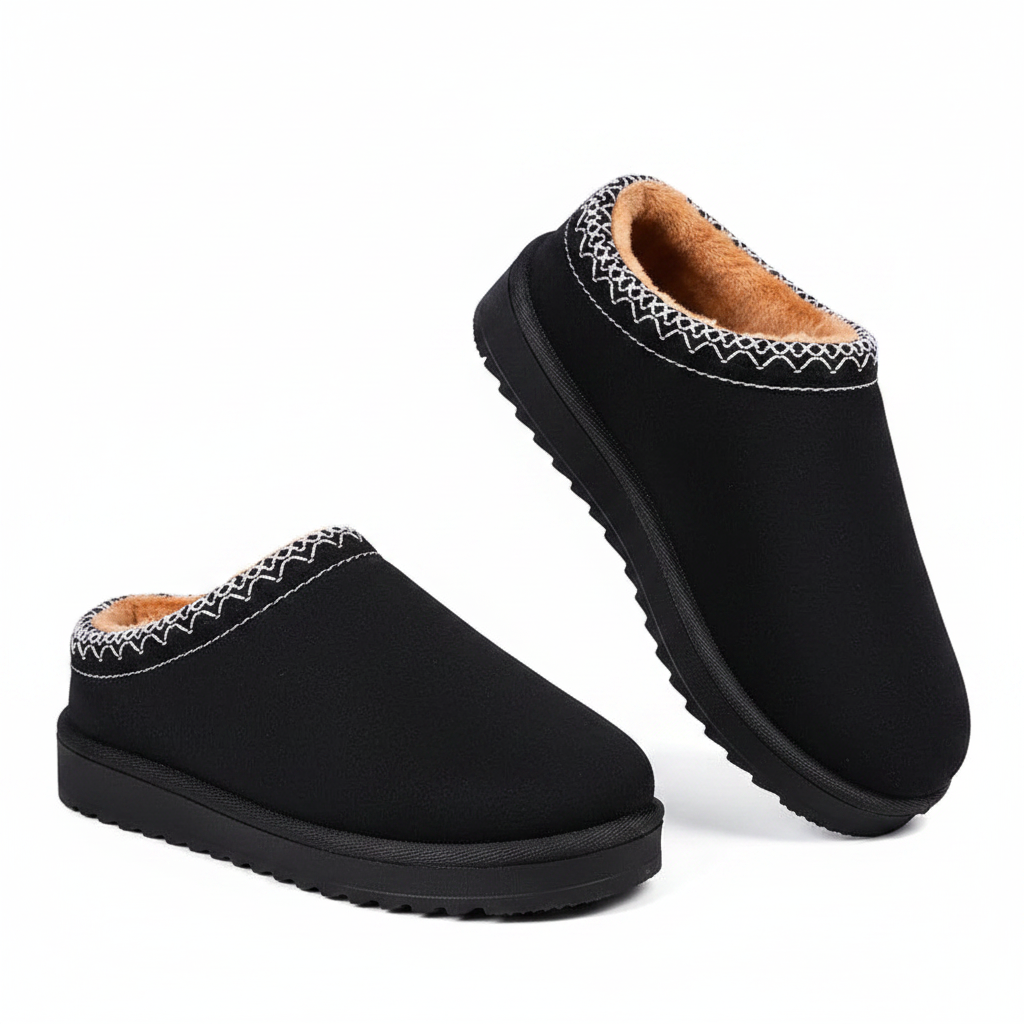 A pair of black slip-on mule slippers with a tan fleece lining and white zigzag stitching around the collar, shown on a clean white background.