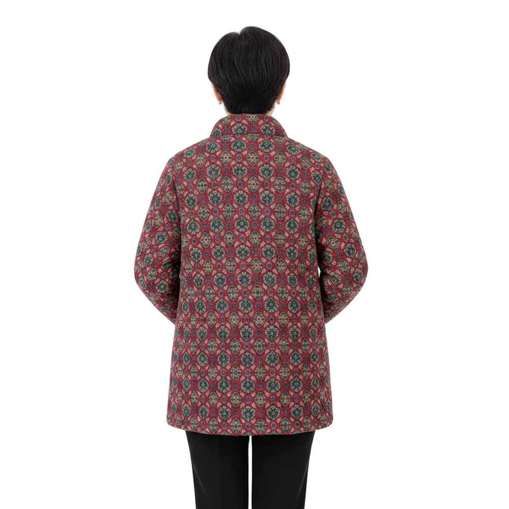 A person shown from the back wearing a patterned quilted jacket with a red base and intricate geometric motifs in green, beige, and blue, paired with black pants, against a plain white background.