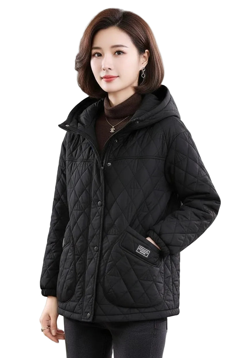A woman wearing a black quilted hooded jacket over a dark brown turtleneck sweater, photographed against a plain white studio background.