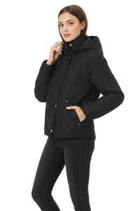 A woman modeling a black quilted hooded jacket with silver snap buttons, paired with black jeans, against a plain white background.