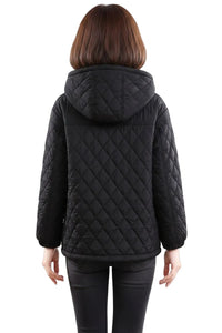 A woman viewed from the back wearing a black quilted hooded jacket and black pants against a plain white background.