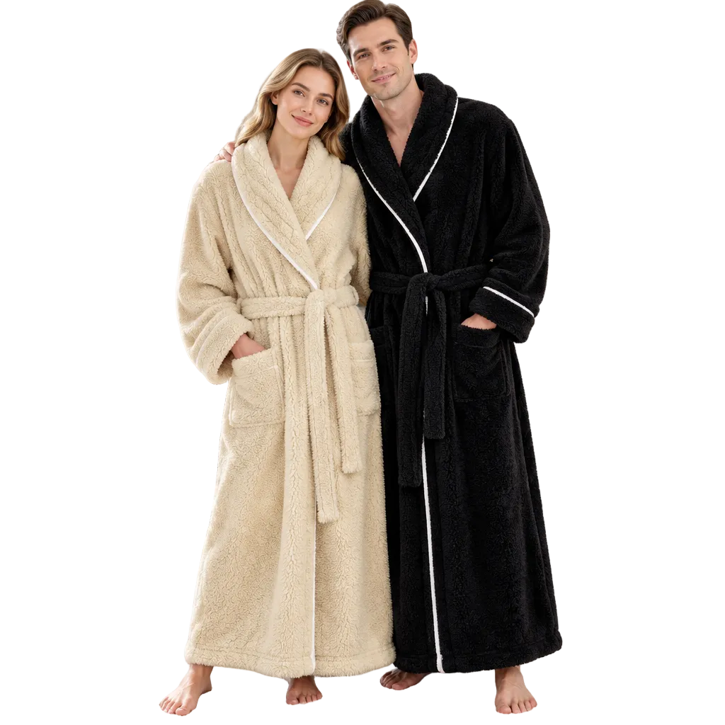 A man and a woman standing barefoot in a bright bedroom, each wearing a plush bathrobe. The woman's robe is cream/beige with white piping, and the man's robe is black with white piping.