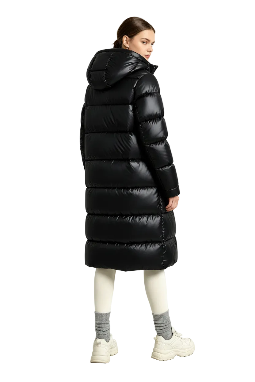 A model is shown from the back wearing a long, shiny black puffer coat, cream leggings, gray socks, and chunky off-white sneakers in a bright, minimalist studio setting.