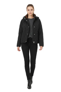 A woman modeling a black quilted jacket with a brown hood lining, worn over a dark gray top and black pants, against a plain white background.