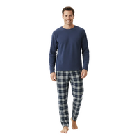 A man modeling a navy blue long-sleeve crewneck shirt and navy blue plaid pajama pants against a plain white studio background.