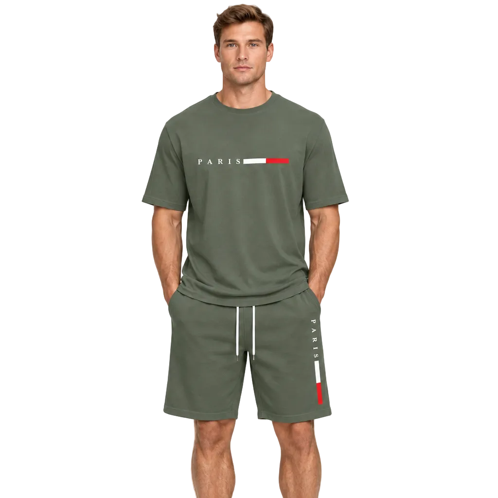 A man modeling an olive green matching lounge set consisting of a short-sleeve t-shirt and shorts. The t-shirt features 'PARIS' printed in white next to a white and red stripe logo, while the shorts have white drawstrings and a vertical white and red 'PARIS' print on the side.