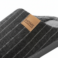 Close-up of a dark gray pinstriped slippershare with a tan faux-leather brand patch reading 'HOME'.