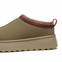 A side profile view of a slip-on platform sneaker in olive green, featuring a red and beige geometric patterned collar trim and a red pull tab on a white background.