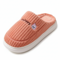 A single pink ribbed knit slip-on house slipper with a white sole, featuring the word 'HAPPY' and a small bunny face embroidered on the side, set against a plain white background.