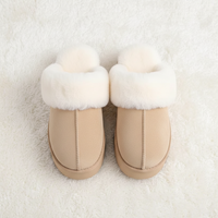 A pair of beige slip-on winter boots with thick white faux-fur trim, photographed from above on a white textured rug.
