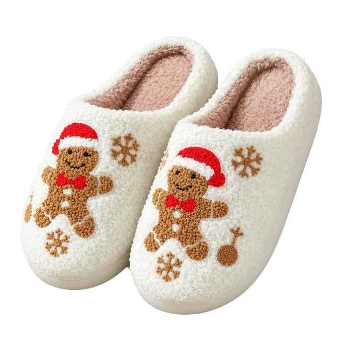 A pair of fluffy white sherpa slip-on slippers decorated with brown gingerbread men wearing red Santa hats, red bow ties, and brown snowflakes, shown on a clean white background.