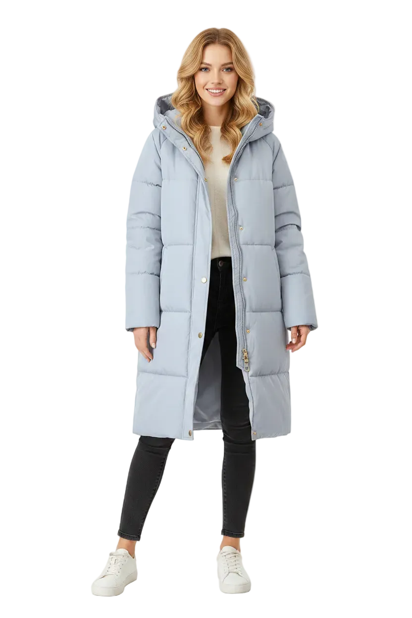 A woman modeling a long, light blue-gray hooded puffer coat with gold-tone buttons, worn over a cream top, black pants, and white sneakers on a plain white studio background.