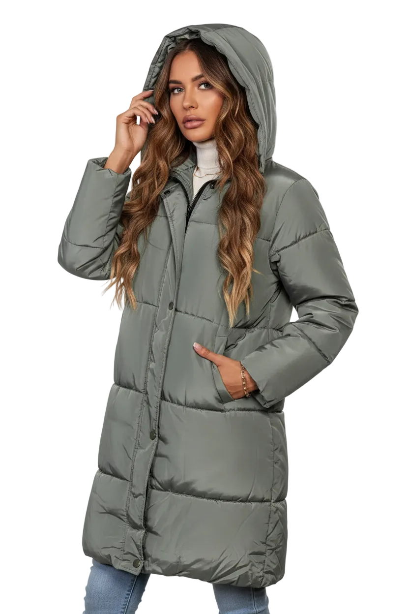 A woman wearing a long, hooded puffer coat in a muted sage green color, paired with a white turtleneck and blue jeans, set against a plain white background.