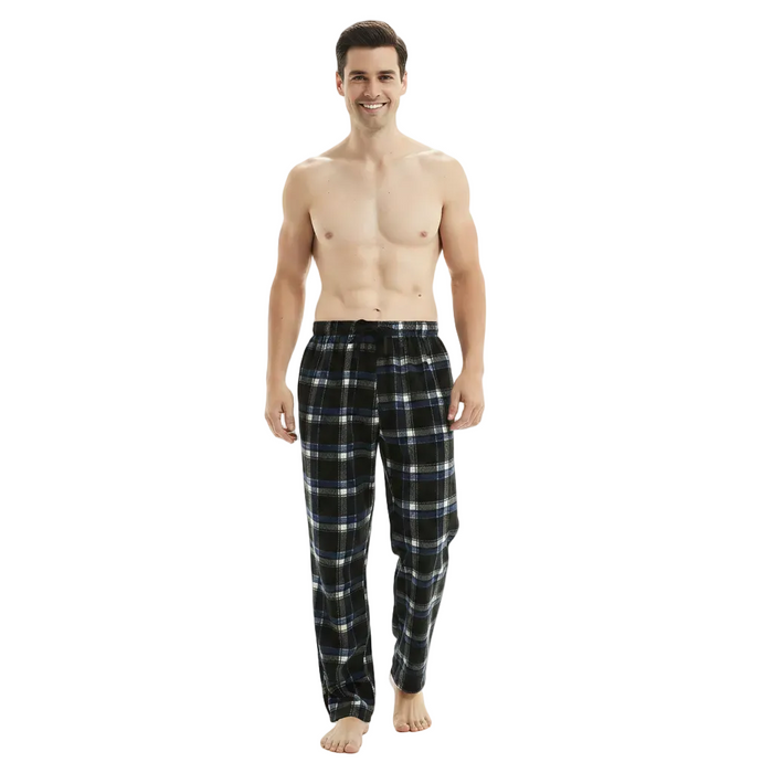 A man modeling a pair of black plaid pajama pants with white and blue lines, standing against a plain white studio background.