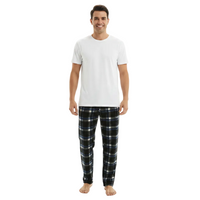 A man modeling a white crew-neck t-shirt and dark plaid pajama pants against a plain white studio background.