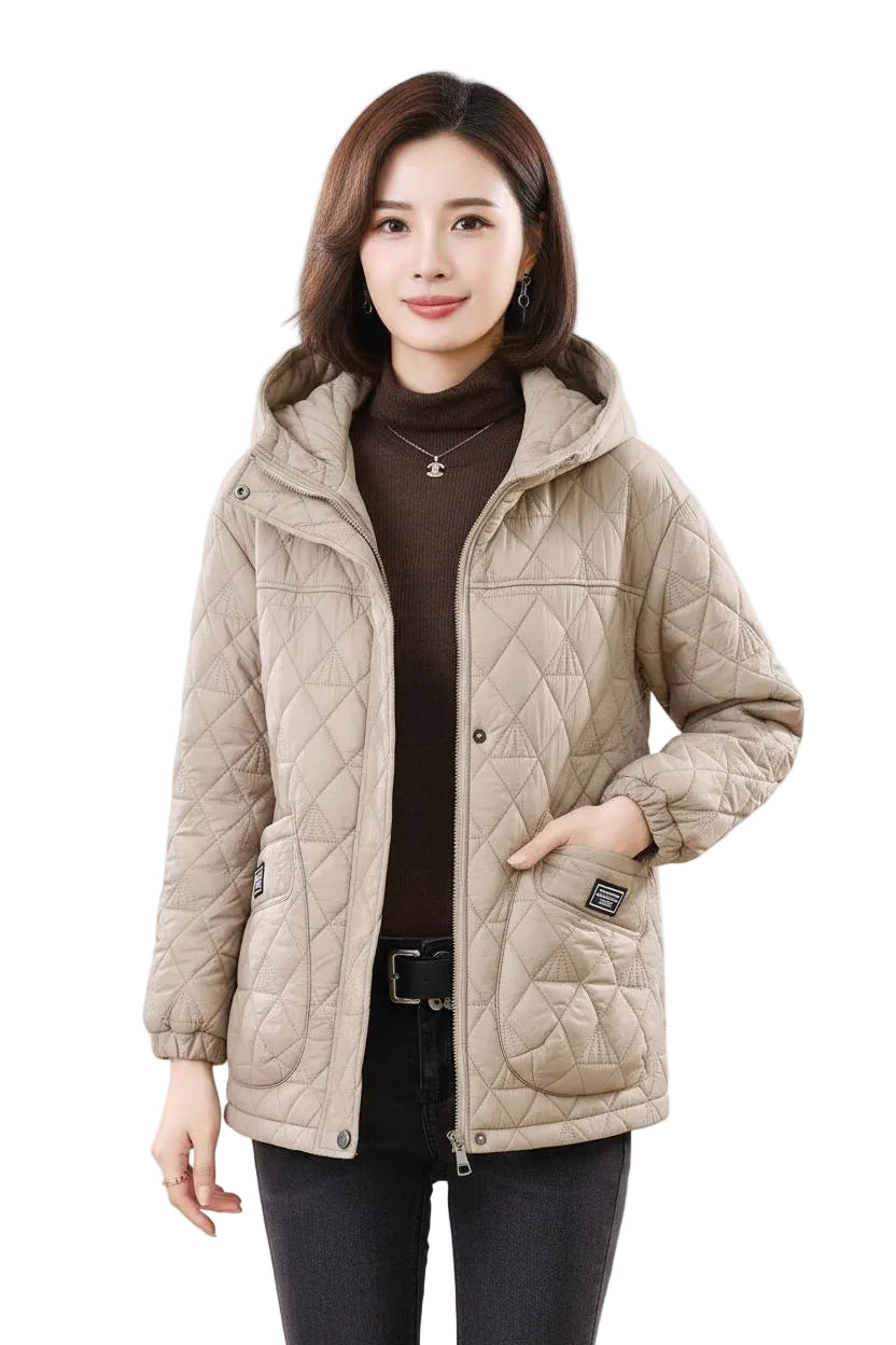 A woman modeling a light beige quilted hooded jacket over a dark brown turtleneck sweater and black pants, set against a plain white background.