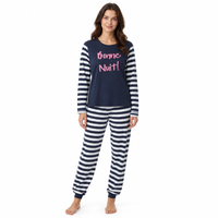 A woman modeling a two-piece pajama set featuring a navy blue top with 'Bonne Nuit!' printed in pink and navy-and-white striped sleeves, paired with matching navy-and-white striped pants, against a plain white background.