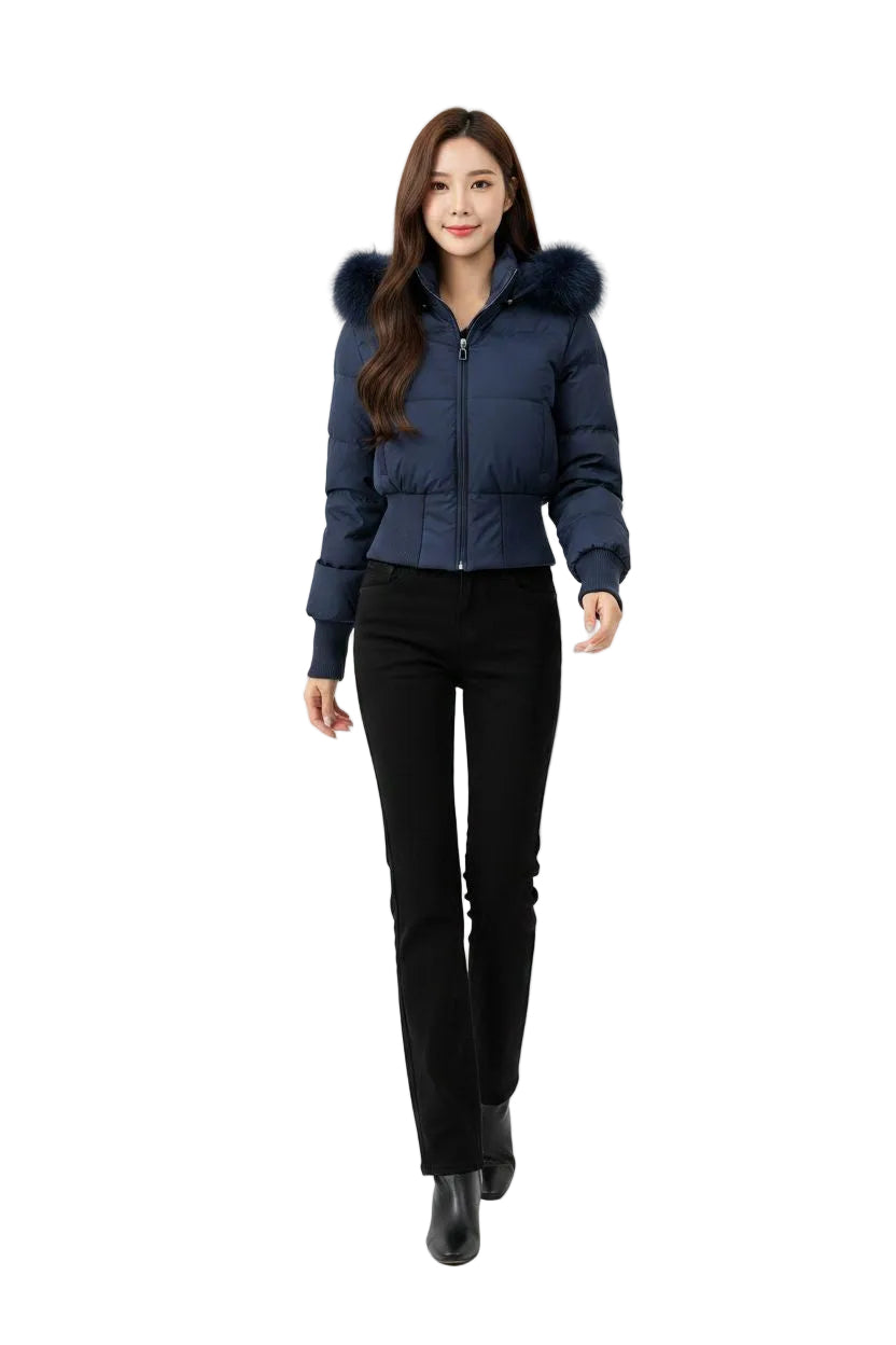 A woman modeling a navy blue puffer jacket with a dark fur-trimmed hood, paired with black pants, against a plain white studio background.