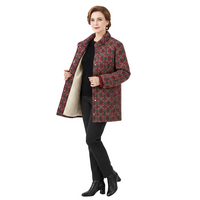 A woman modeling a patterned quilted winter coat with a beige lining, worn over a black top and black pants, against a plain white background.