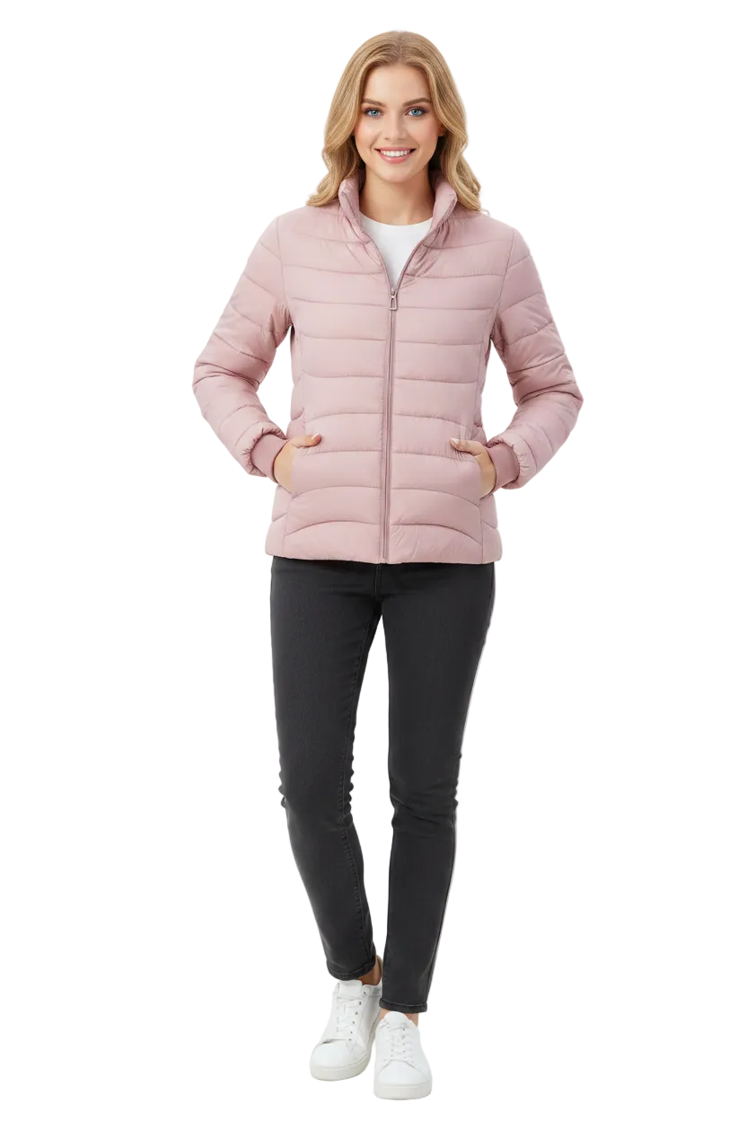A woman modeling a light pink puffer jacket with a front zipper, paired with black skinny pants and white sneakers, against a plain white studio background.