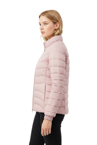A woman shown in side profile wearing a light pink puffer jacket and black pants against a plain light gray studio background.