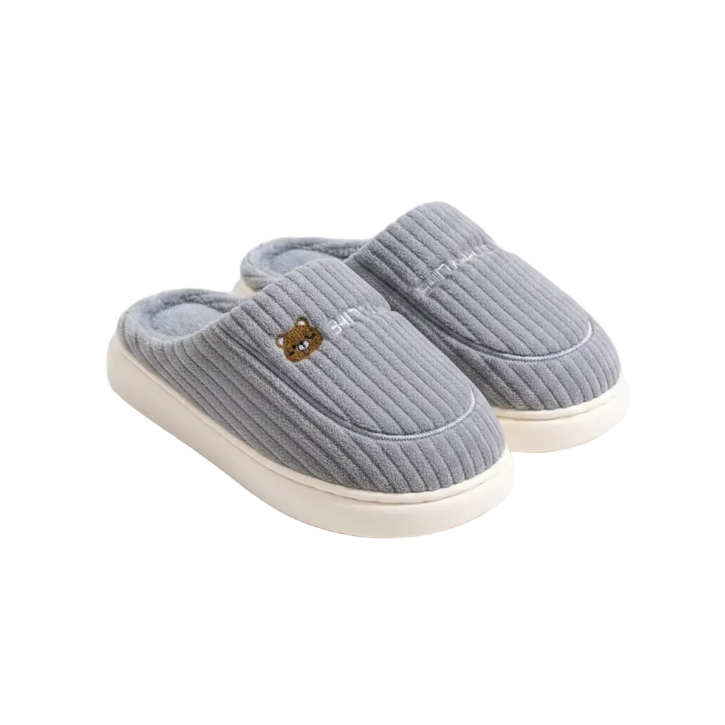 A pair of light gray ribbed knit slip-on slippers with cream-colored soles and a small embroidered bear face detail on the front slipper, shown on a clean white background.