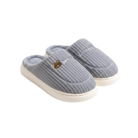 A pair of light gray ribbed knit slip-on slippers with cream-colored soles and a small embroidered bear face detail on the front slipper, shown on a clean white background.